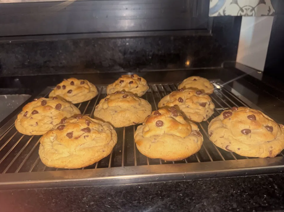 Fornada de cookies gigantes com gotas de chocolate esfriando na grade
